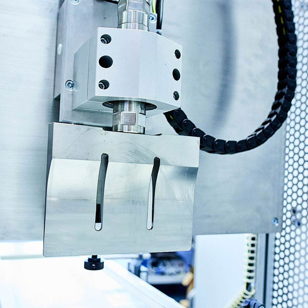 Detailaufnahme eines metallischen Ultraschall-Schweißkopfs mit linearer Führung und flexibler Kabelführung.