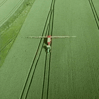 Agrarmaschine, die über ein grünes Feld fährt