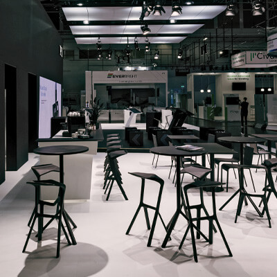 Moderner Messestand mit schwarzen Stehtischen und Hockern in stilvollem Design.