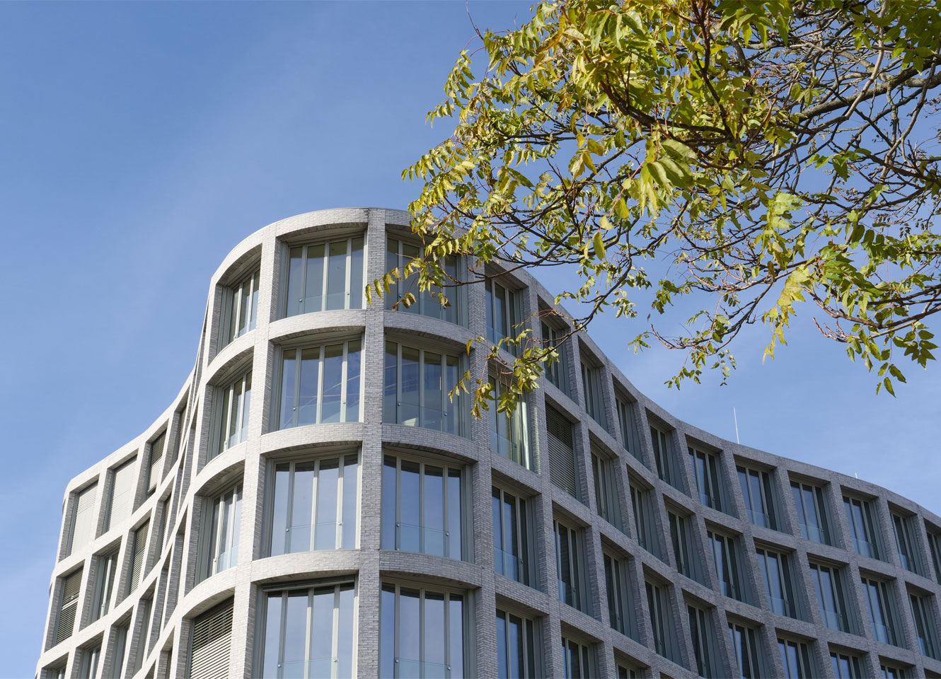 Modernes Verwaltungsgebäude der Stadt Pforzheim mit Glasfassade und geschwungener Architektur vor blauem Himmel