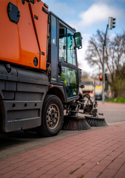 Orangefarbene Kehrmaschine der Stadt Pforzheim bei der Straßenreinigung.