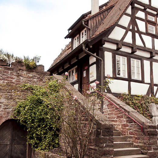 Fachwerkhaus mit Sandsteinmauer und Treppe im Vordergrund